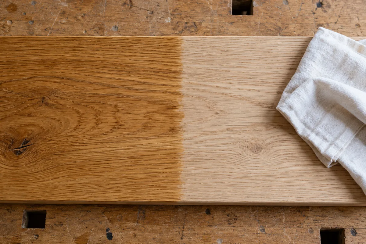 Lame de parquet en chêne poncée, à moitié huilée, à côté d&rsquo;un chiffon de coton blanc plié